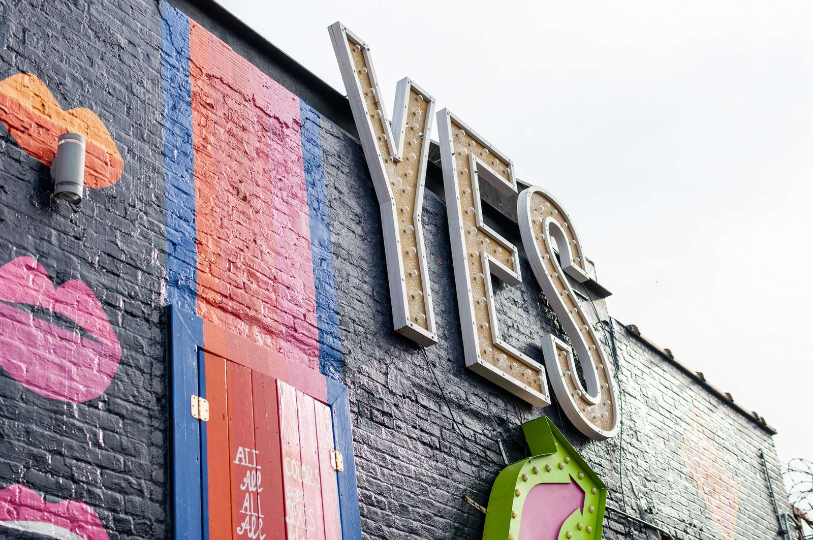 YES neon sign on painted brick exterior