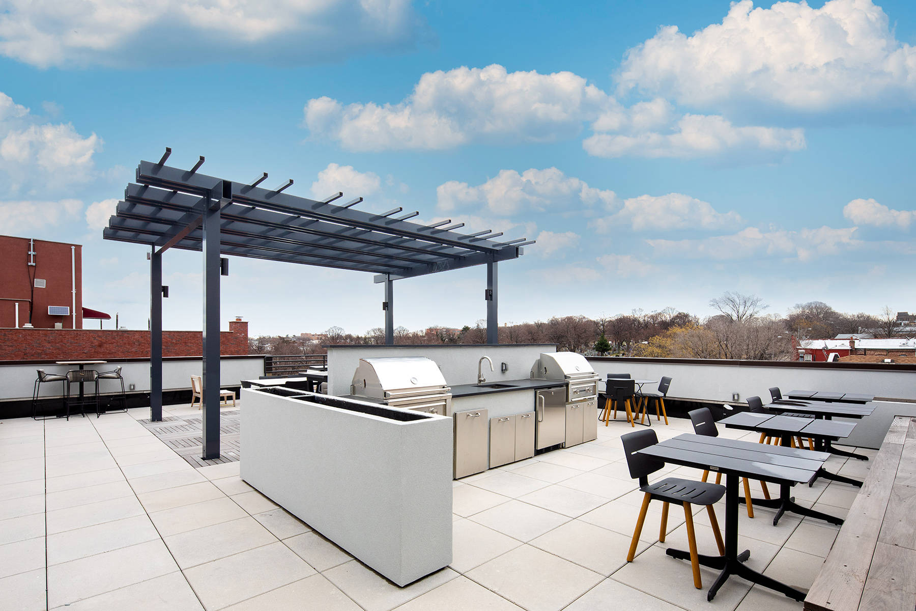 Rooftop with tables and seating and large grills with sink and counters