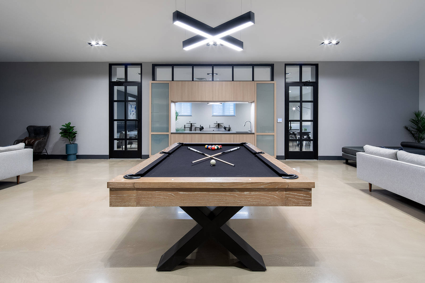 Game room with modern billiards table and view of kitchen behind it